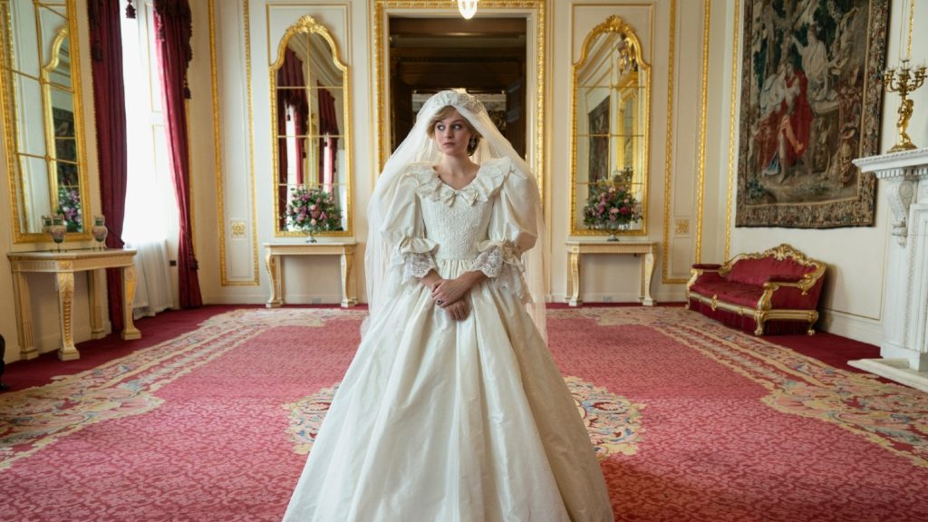 A bride in a vintage-style wedding dress reminiscent of Princess Diana's best moments, standing in an ornate room with classic decor.