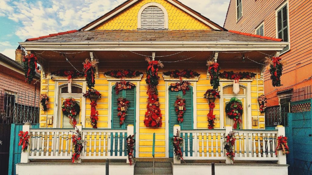 A vibrant yellow house adorned with festive holiday decorations and Christmassy wreaths.