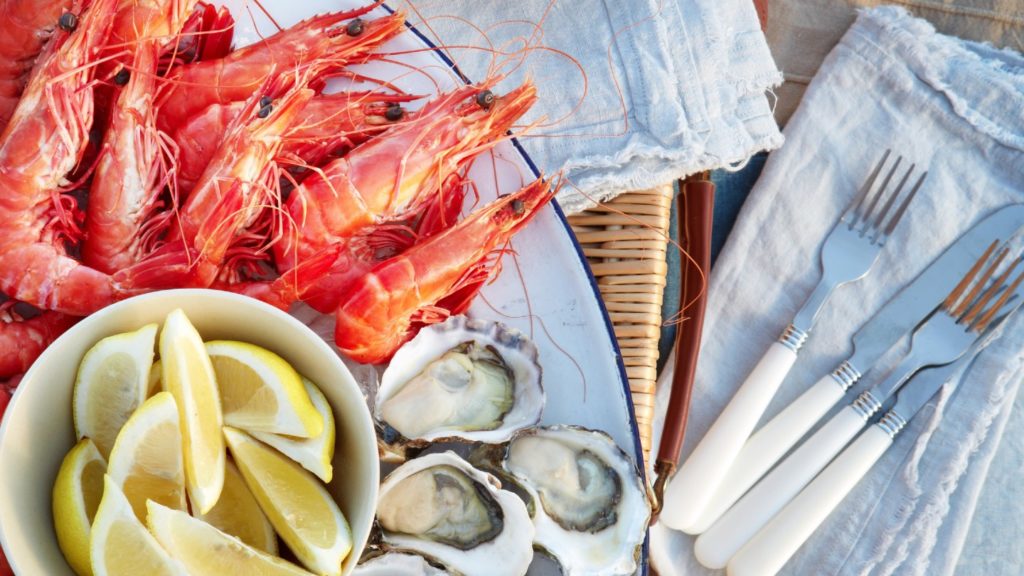 A Christmas seafood spread in Sydney featuring fresh prawns and oysters accompanied by lemon wedges, with cutlery on the side.
