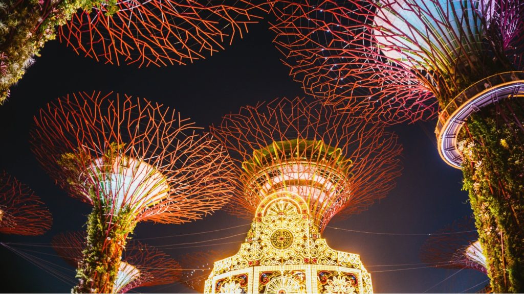 Illuminated artificial trees and a lit festive tower at night against a dark sky, celebrating Asian Christmas traditions.