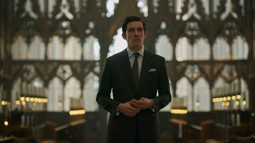 A man in a suit standing solemnly in an ornate church during a scene from The Crown Season 4.