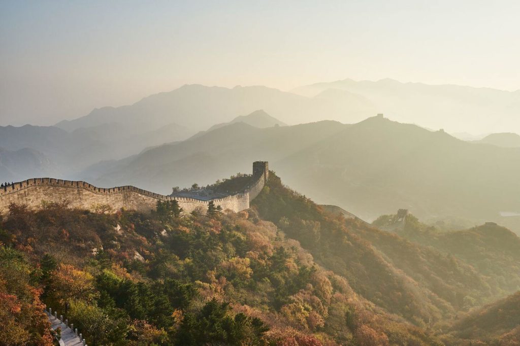 The great wall of china meandering through a mountainous landscape at sunset, illuminated by Trafalgar Black Friday travel deals.