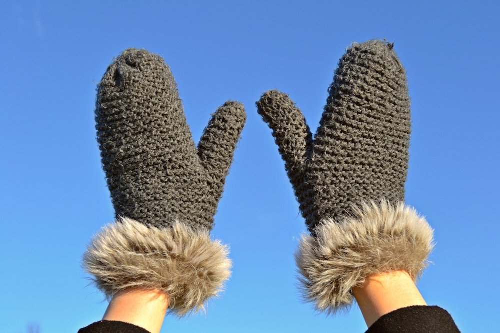 Two grey wool mitts with faux fur.