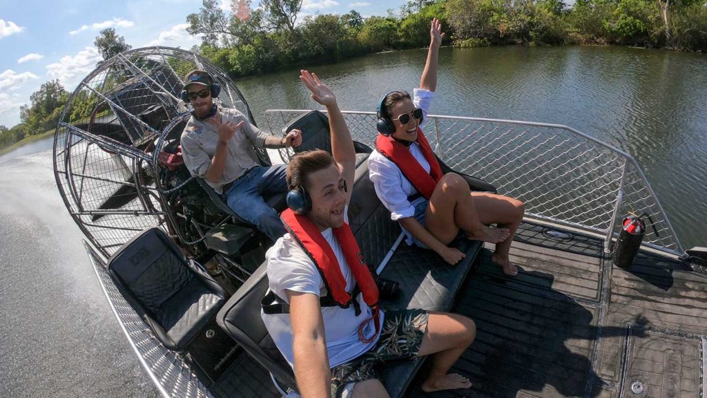 Three people enjoying an airboat ride on a sunny day in the outback Australia.