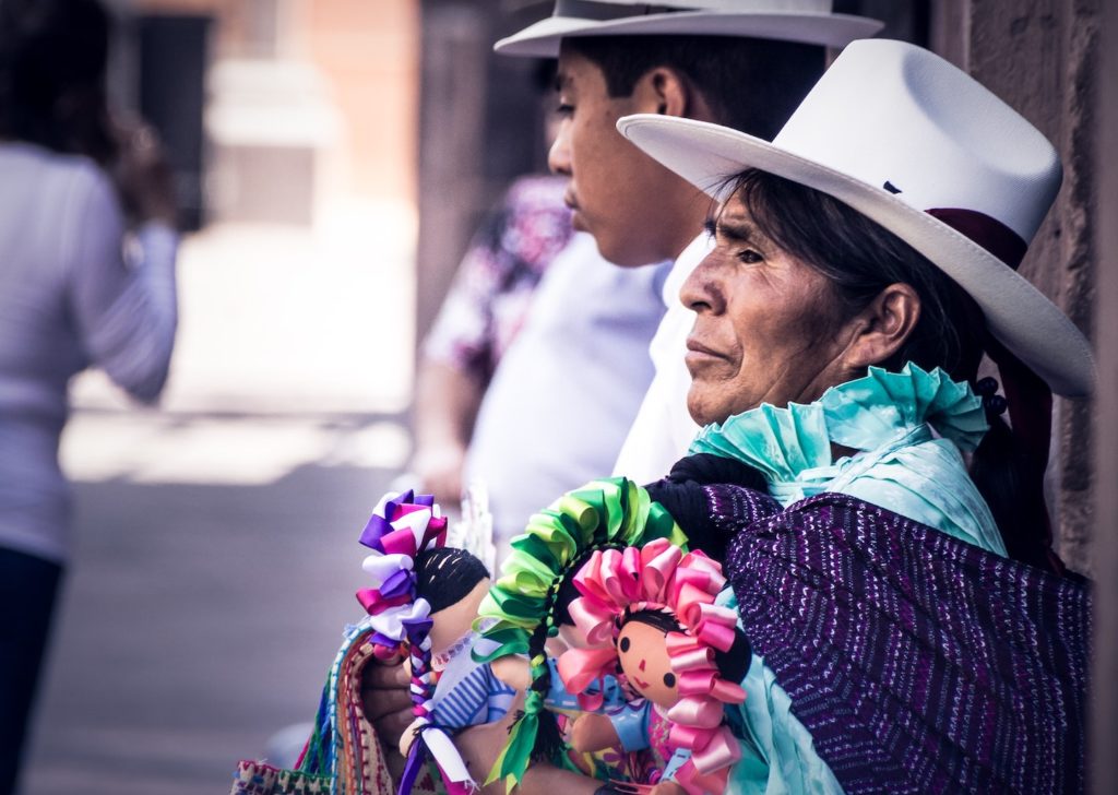 Woman in traditional attire selling colorful handicrafts on a street during a trip to South America.