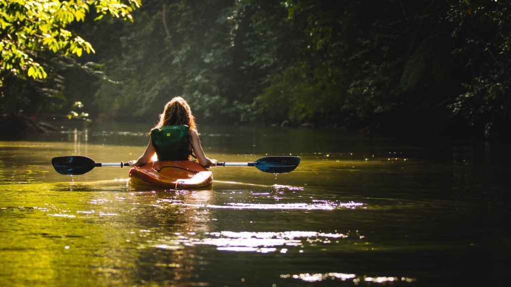 A person kayaking on a tranquil river surrounded by lush forest during their 10-day trip to Costa Rica.