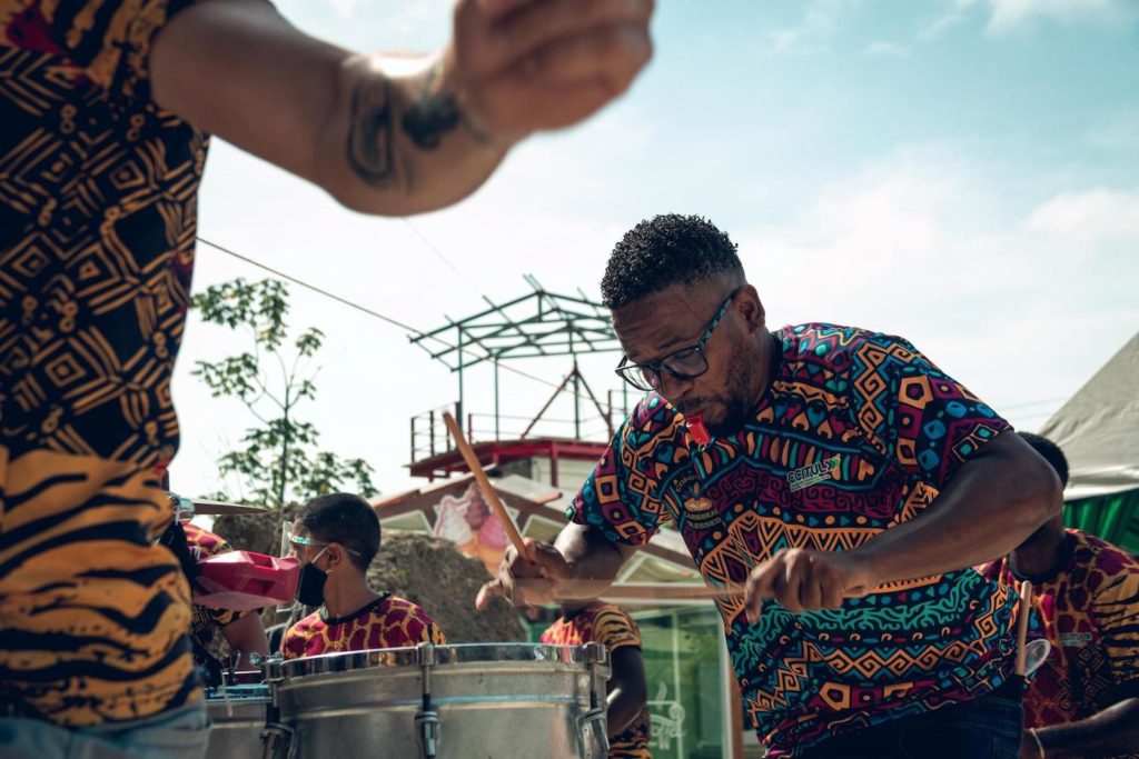 Men in vibrant clothing enthusiastically playing drums at a Costa Rica outdoor event.