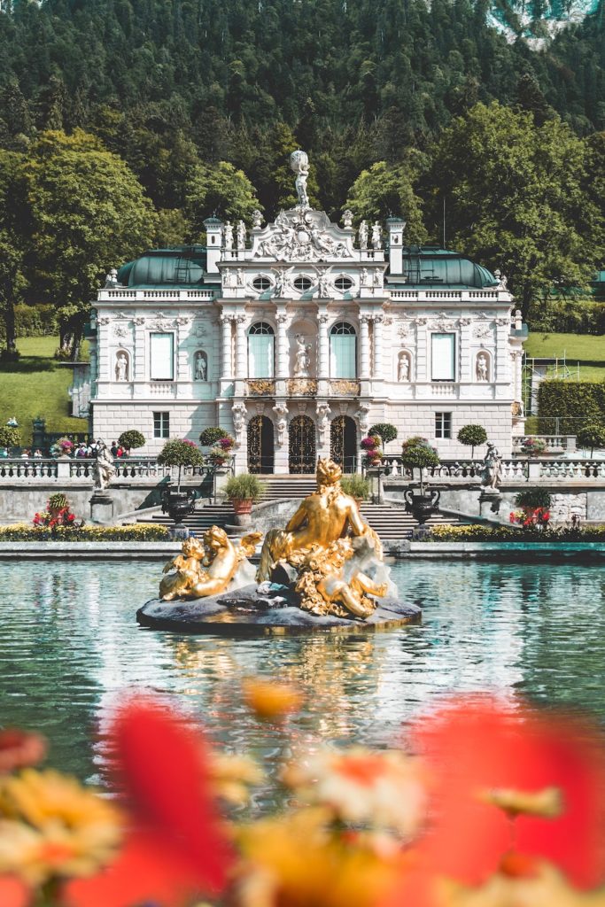 Opulent Bavarian baroque palace with a gilded fountain set amidst lush gardens.