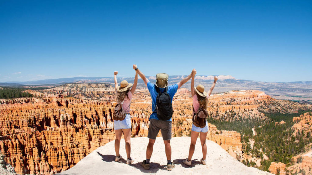 Family celebrating and raising hands after hiking up to the top of Bryce Canyon National Park, Utah, USA.