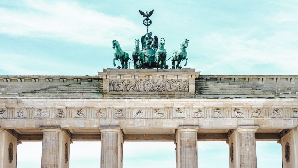 Visit the Brandenburg Gate from the US, topped with quadriga statue under a clear sky.