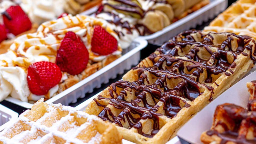 Assorted Belgian waffles topped with whipped cream, strawberries, bananas, and the best chocolate in the world as sauce.