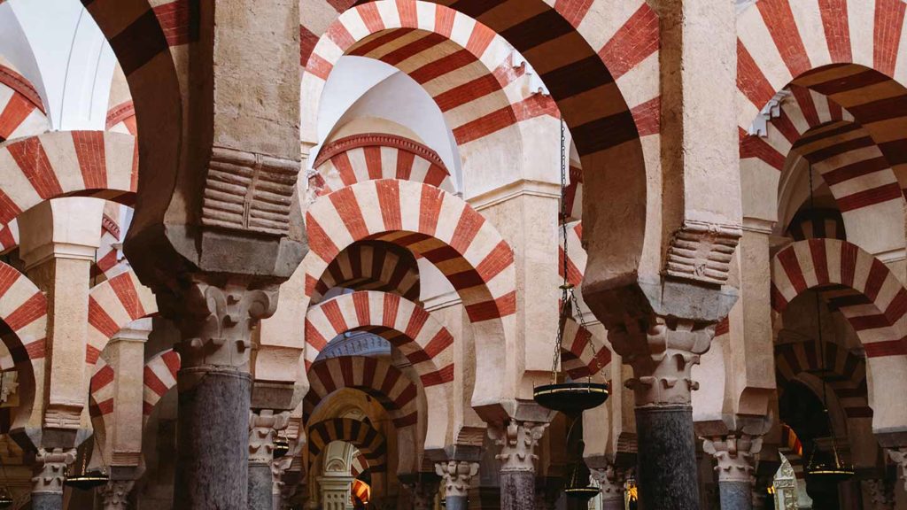 Arched hall bathed in the winter sun, with red and white striped arches in the mosque-cathedral of Córdoba, Spain.
