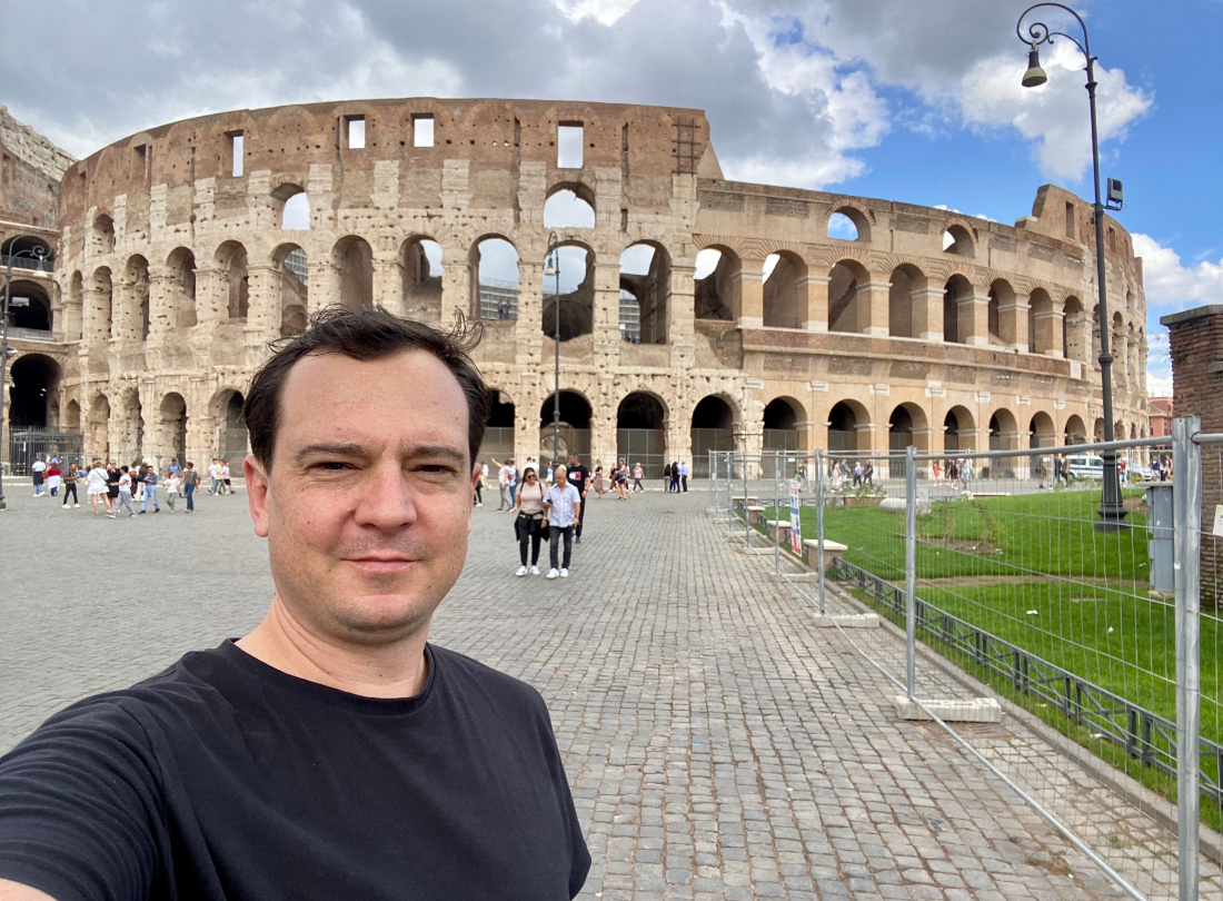 Man taking a selfie in front of the colosseum in rome.