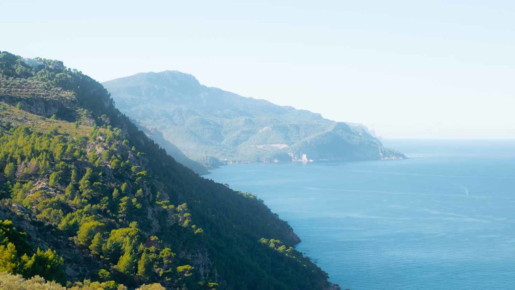 Coastline with mountains and sea under a hazy sky.