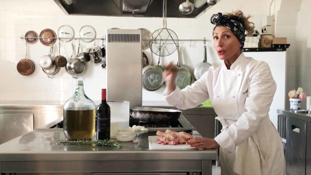 A chef in a white uniform preparing the best Tuscan recipes in a commercial kitchen.