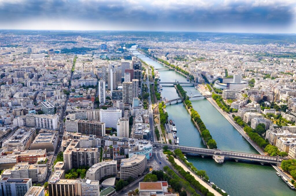 Aerial view of a cityscape with the Seine river flowing through it, flanked by buildings and crossed by bridges in the Paris artists quarter.