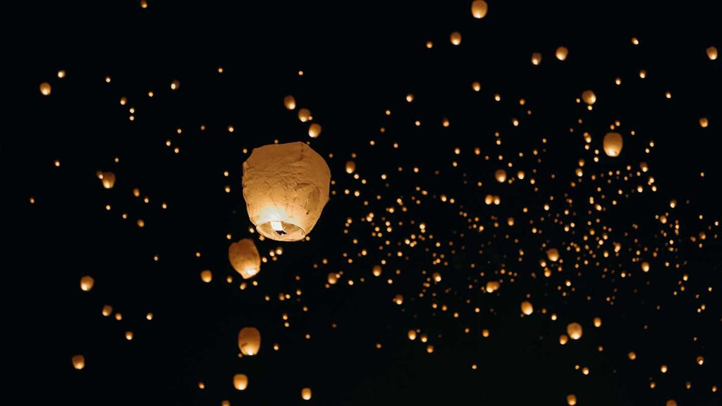 Many glowing paper lanterns floating in a dark night sky, creating a magical constellation of lights at one of the bucket list events.