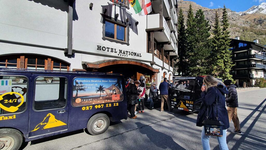 Guests boarding a taxi outside Hotel National with a clear view of the mountains in the background, guided by their Trafalgar travel director.
