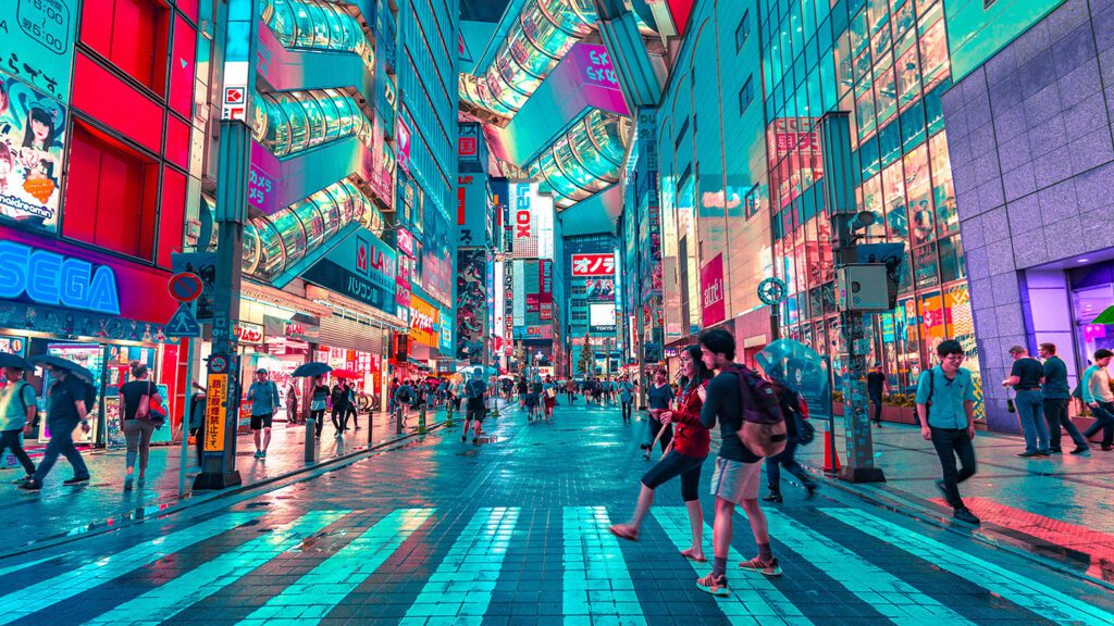 Vibrant street scene in Tokyo at night with illuminated signs, crowds, and a wet pavement reflecting colorful lights, showcasing why it's a must-visit destination when you travel to Japan.