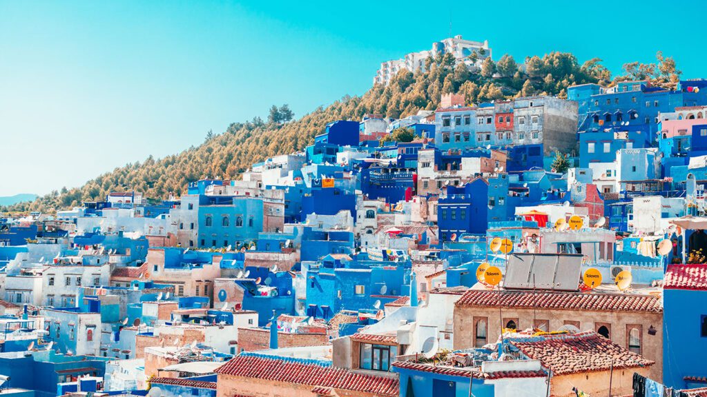 Hillside of blue and white-painted houses against a blue sky