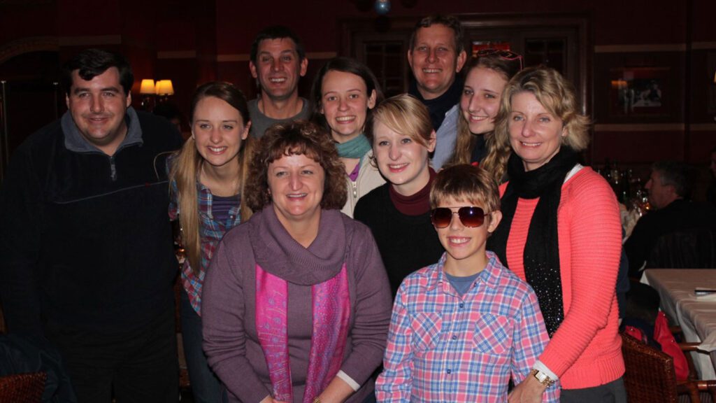 Group of ten best friends posing for a photo in a restaurant, with some smiling at the camera.
