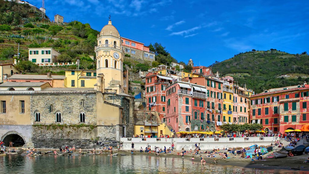 Colorful buildings and a crowded beach in a coastal village under a clear blue sky, epitomizing the best beaches of Europe.