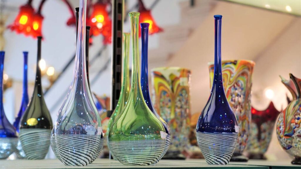 Blown glass art vases on display, featuring intricate patterns and varying shapes, in a well-lit indoor setting.