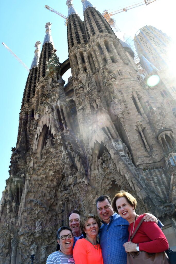 A group of friends traveling and smiling in front of the Sagrada Familia. 