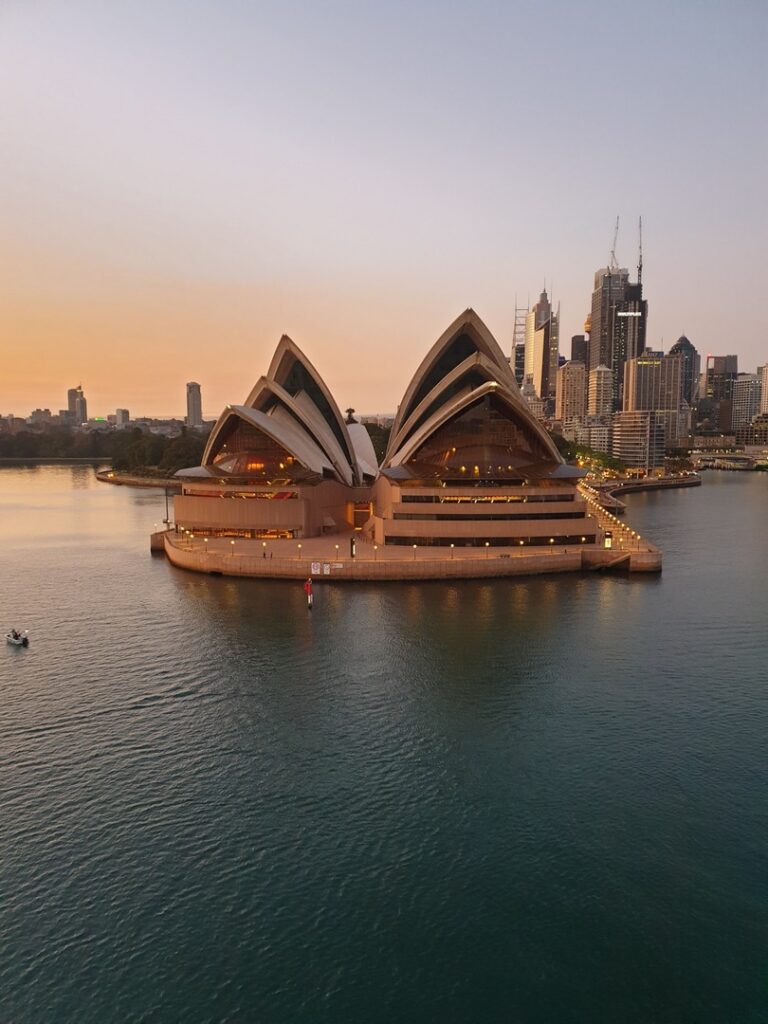 Sunset view of the Sydney Opera House, a popular film location, with the city skyline in the background, reflecting golden hues on the water.