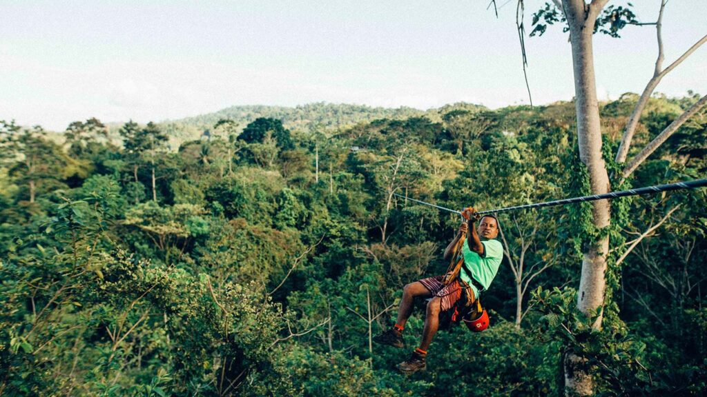 A man ziplining through the canopy of trees in the Costa Rican forest