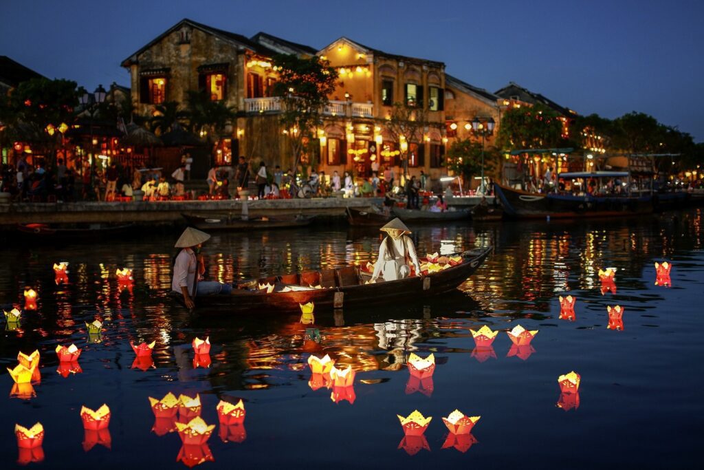 Vietnamese people on boat surrounded by candles