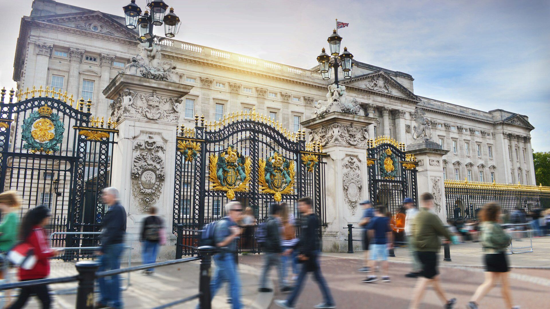 Buckingham Palace with crowds walking in front of it 