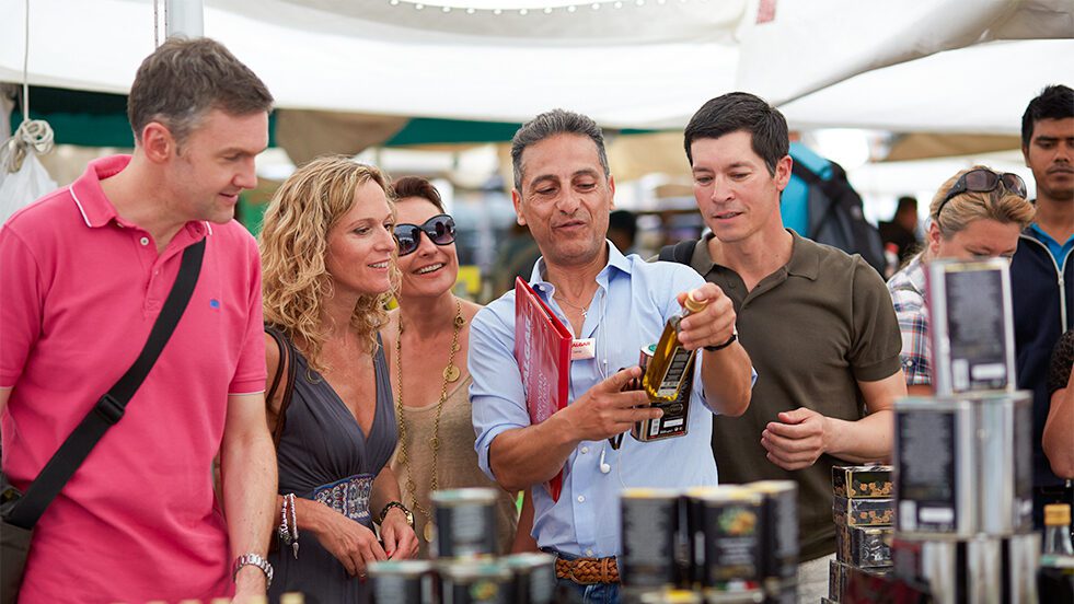 A group of people at a bustling European outdoor market, enjoying the diverse selection of food.