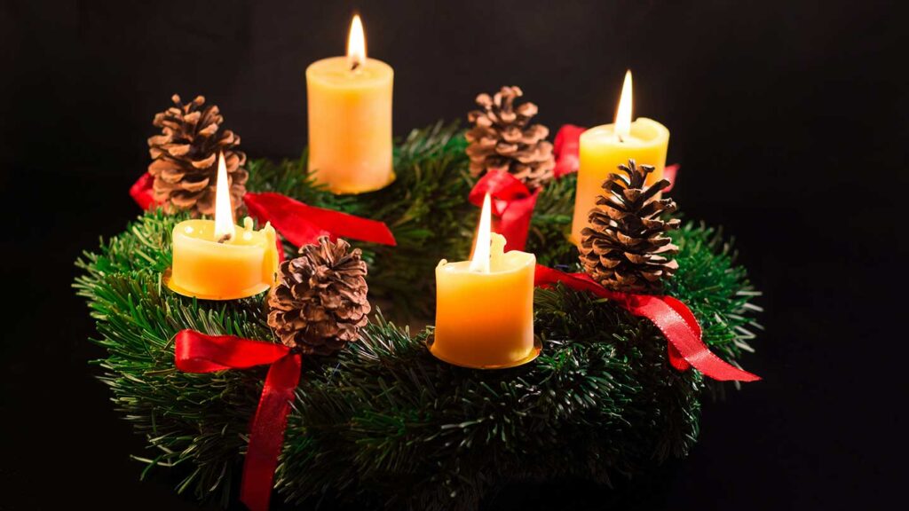 Four lit candles representing the four Sundays of Advent on an Advent wreath.