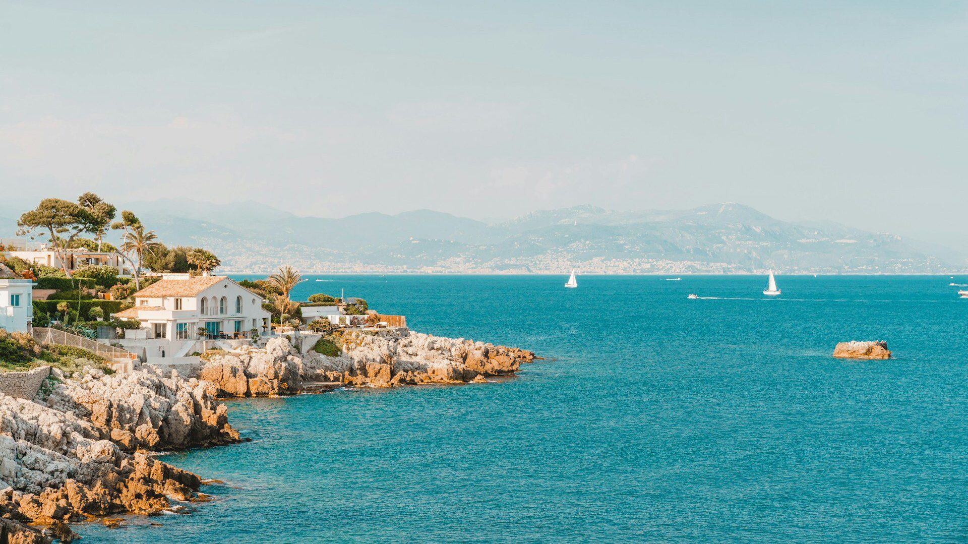 View of the rocky cost of Antibes with a house overlooking blue water 