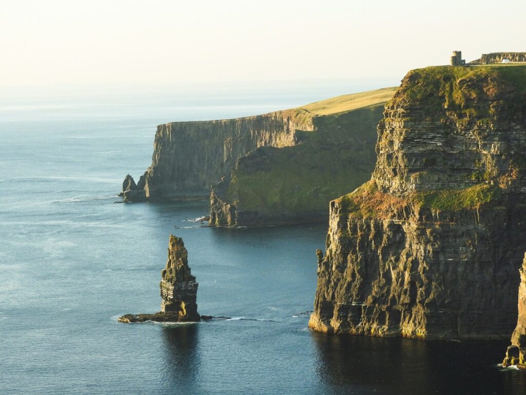 Cliffs of Moher at sunset during spring tours, with calm sea and distinct sea stacks, viewed on a clear day.