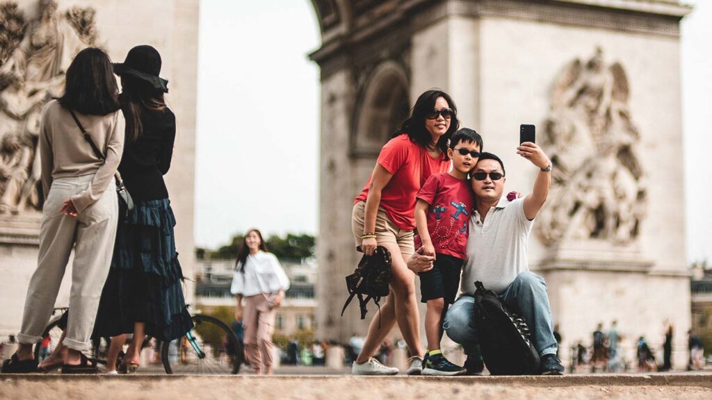 Family posing for a photo in front of l'arc de triomphe in Paris