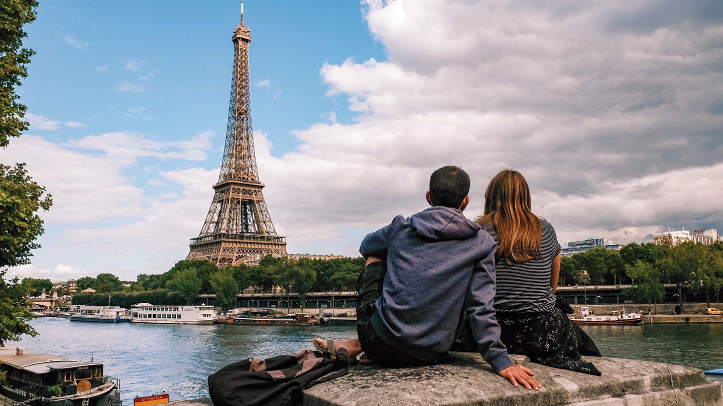 A couple embracing in front of the Eiffel Tower in Paris, France. 