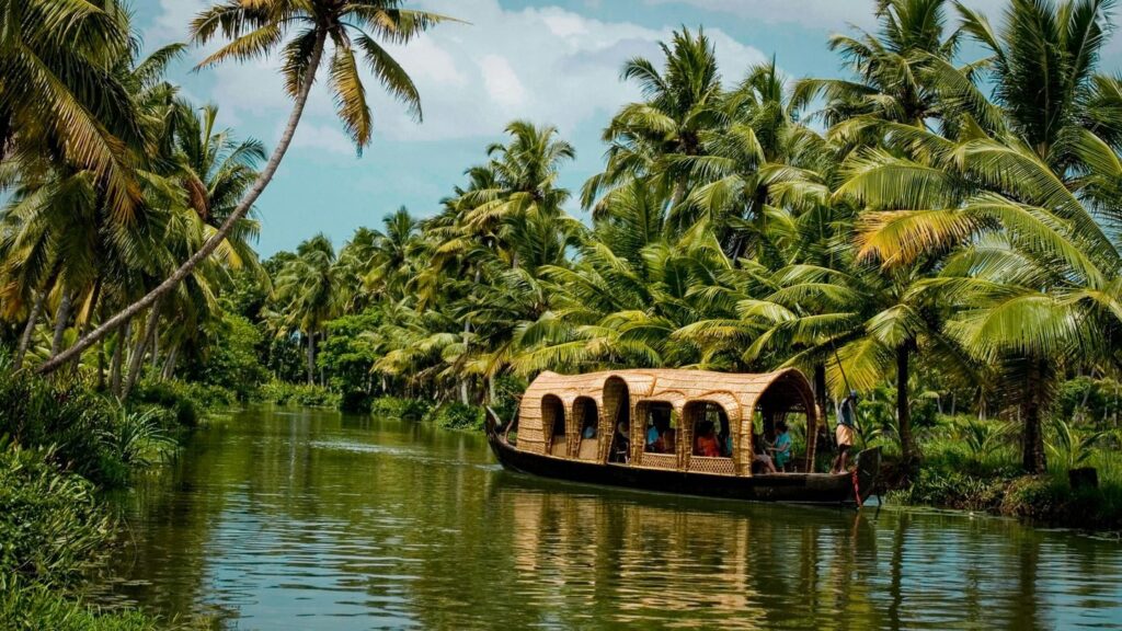 A houseboat in Kerala drifting calmly through a tree-lined waterway.