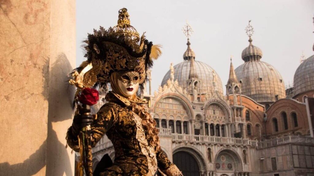 A woman in an ornate costume stands in front of a building.