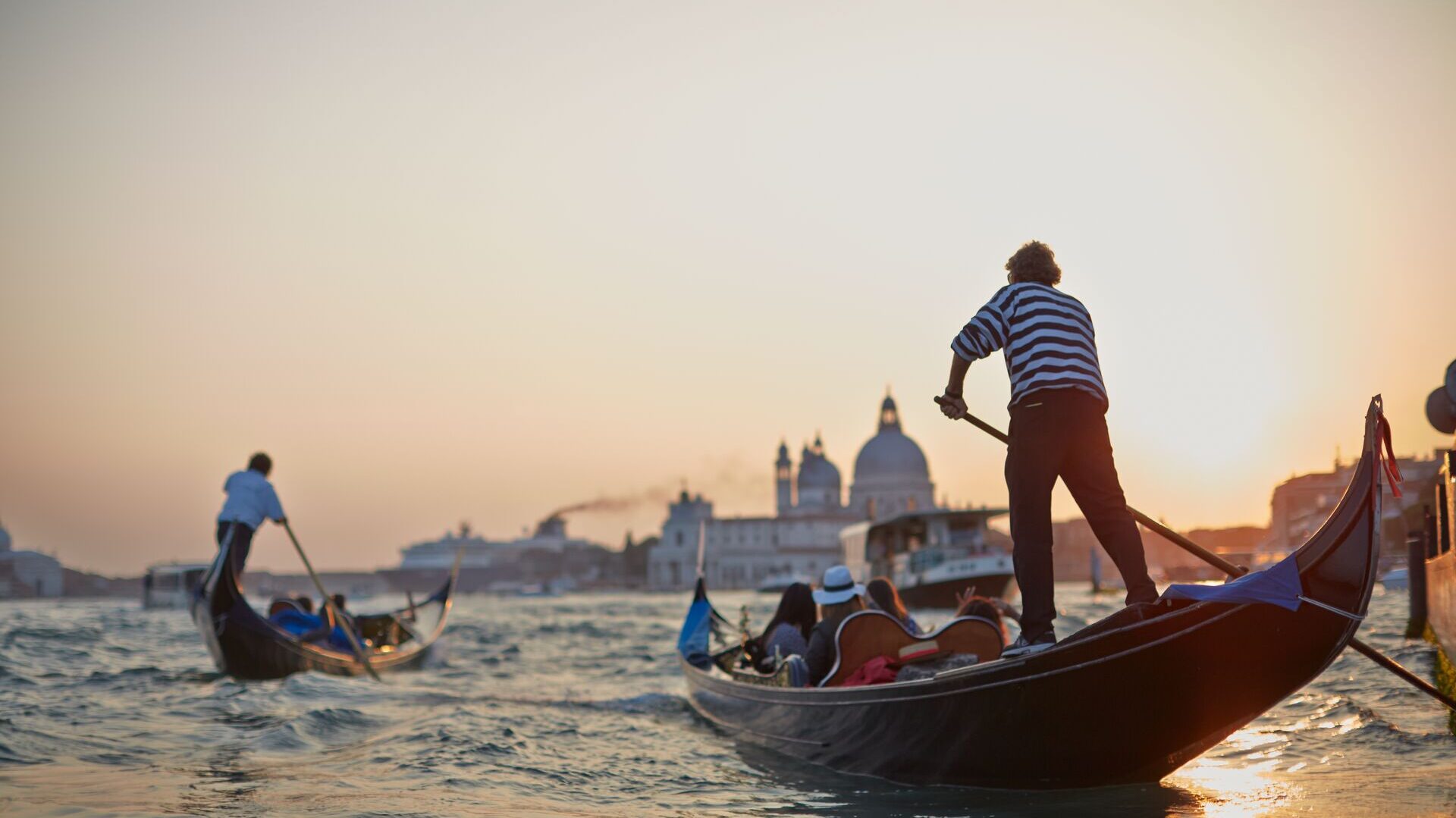 Gondoliers ferry tourists across the Grand Canal in Venice
