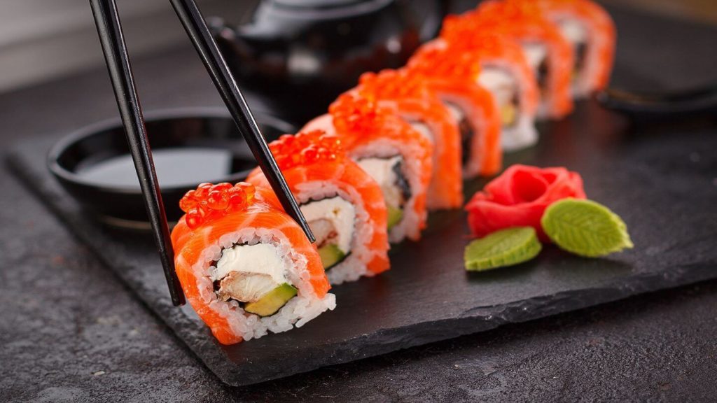 chopsticks holding Japanese sushi