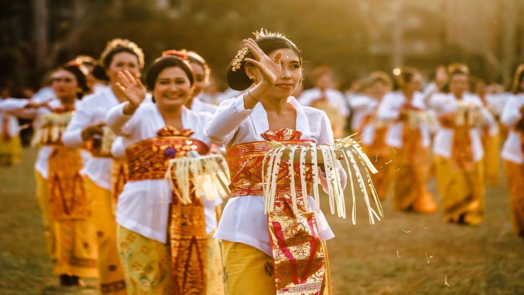 A group of women in traditional attire dancing in a field highlights the cultural richness and beauty that attracts tourists to the area, showcasing the advantages of tourism.